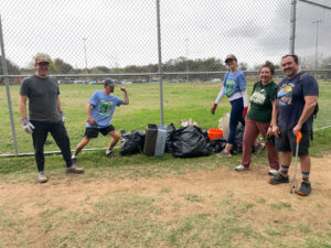 A group of six volunteers posing in front of bags of trash they have picked up.